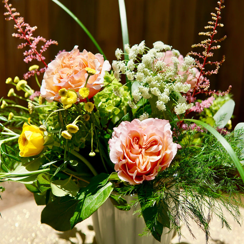 Bouquet of flowers in a white vase against a wooden background