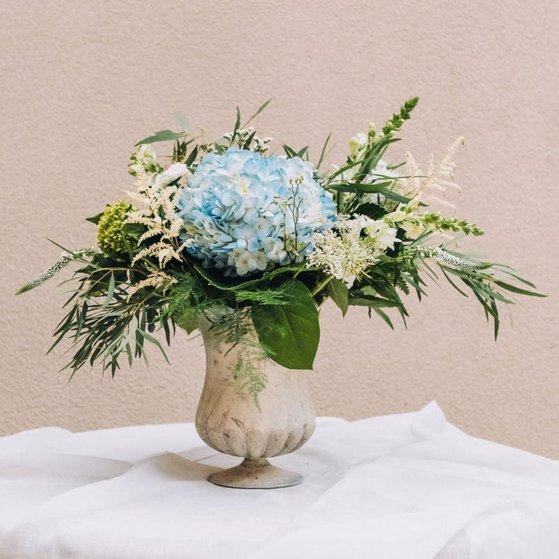 A delightful blend of blue and white blossoms graces a footed vase with an antique finish, exuding timeless charm. Named for a vibrant northwest Georgia city renowned for its pivotal role in the Civil War.