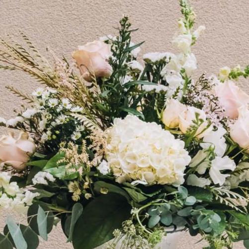 A romantic blend of soft pink and pristine white blossoms, intertwined with lush, luxurious greenery, rests gracefully in a sleek concrete urn, exuding an air of refined elegance. Inspired by a charming central Georgia city, renowned as the backdrop for beloved films like Driving Miss Daisy and Fried Green Tomatoes.