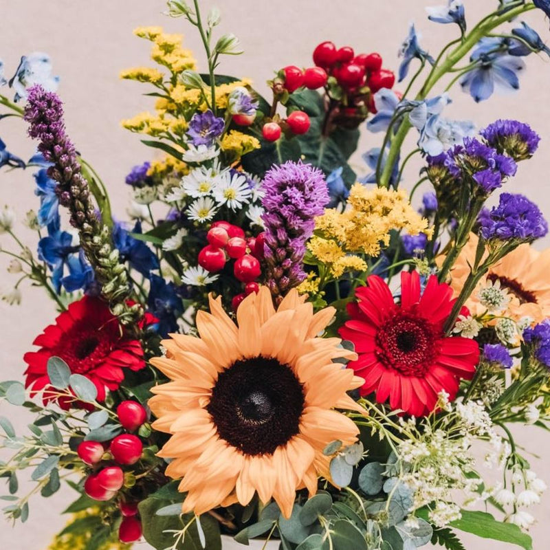 Pronounced "vy-anna," this arrangement bursts with a vibrant medley of sunny yellow, fiery red, deep blue, and regal purple blooms, all artfully composed in a sleek vase that reimagines the timeless double-handled urn. Inspired by a quaint south-central Georgia city renowned for its legendary BIG PIG JIG barbecue championship.