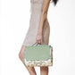 Sage green and cream floral picnic blanket with daisy print, rolled and held in folded canvas carry case with handles.