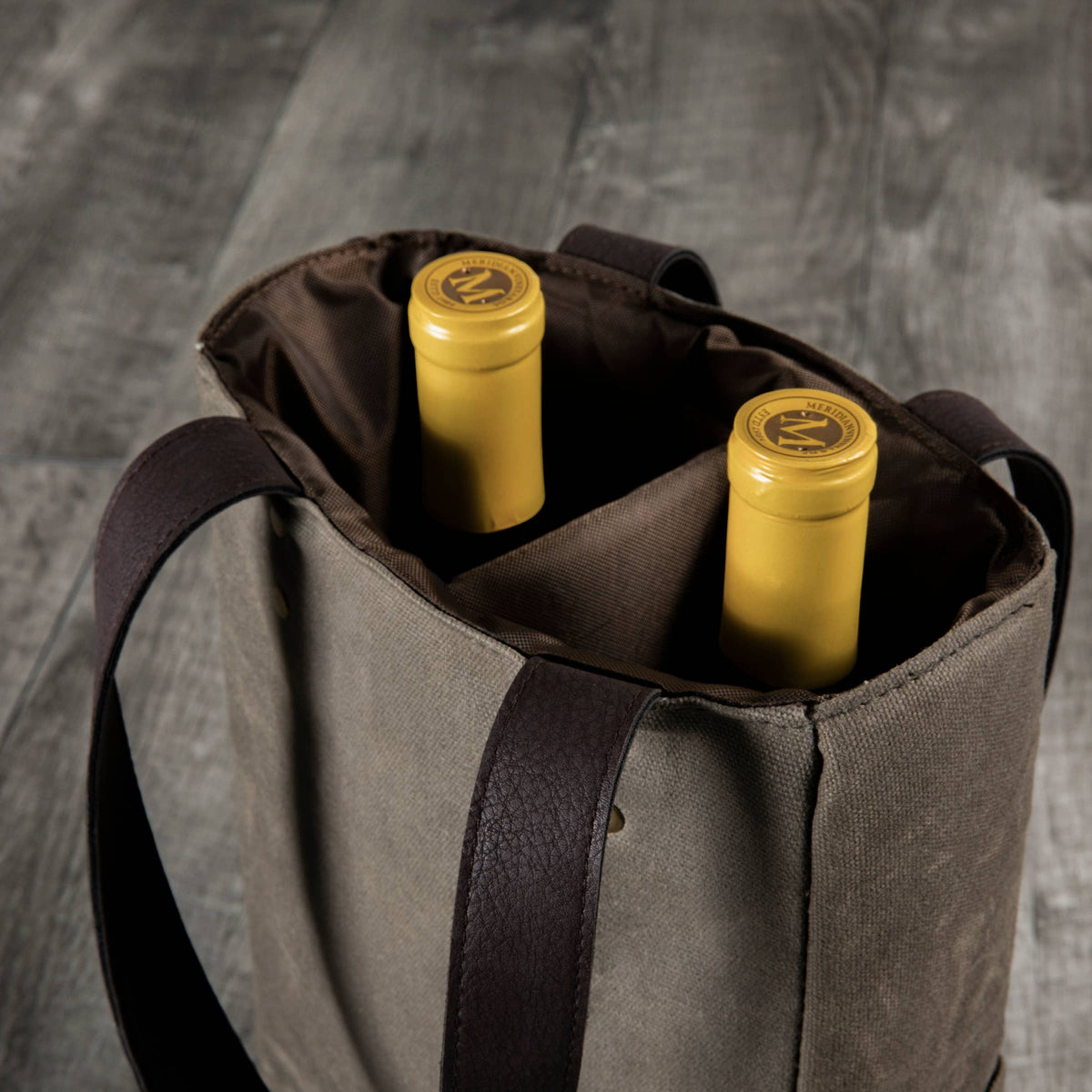 Beige insulated wine tote with dark brown handles holding two bottles of yellow-labeled wine