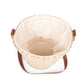 Beige handwoven rush bucket tote with cream lining and brown leather handles, viewed from above with open top.