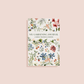 My Gardening Journal with cream cover featuring botanical watercolor flowers in red, blue, orange, and green illustration
