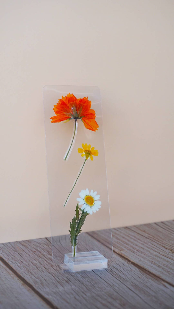 Clear acrylic bookmark with pressed orange, yellow, and white flowers arranged vertically with green stems on white base