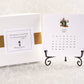 A 2025 calendar with easel, featuring a card with garden motifs for each month, displayed alongside its packaging.