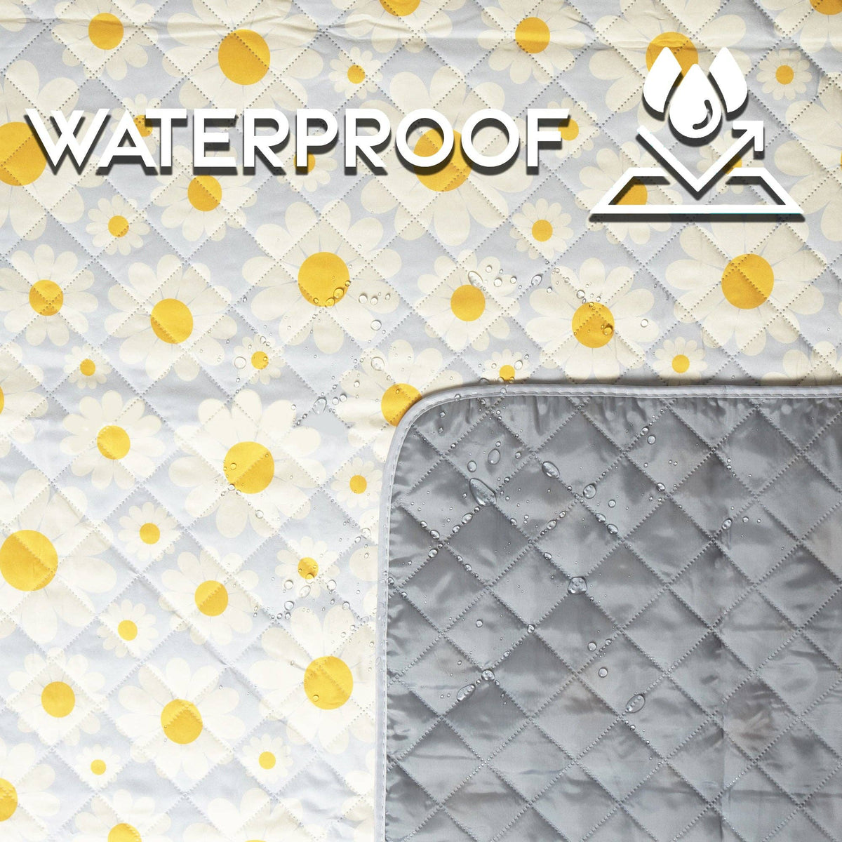 White quilted picnic blanket with yellow daisy print and waterproof gray backing, folded to show both sides with water droplets
