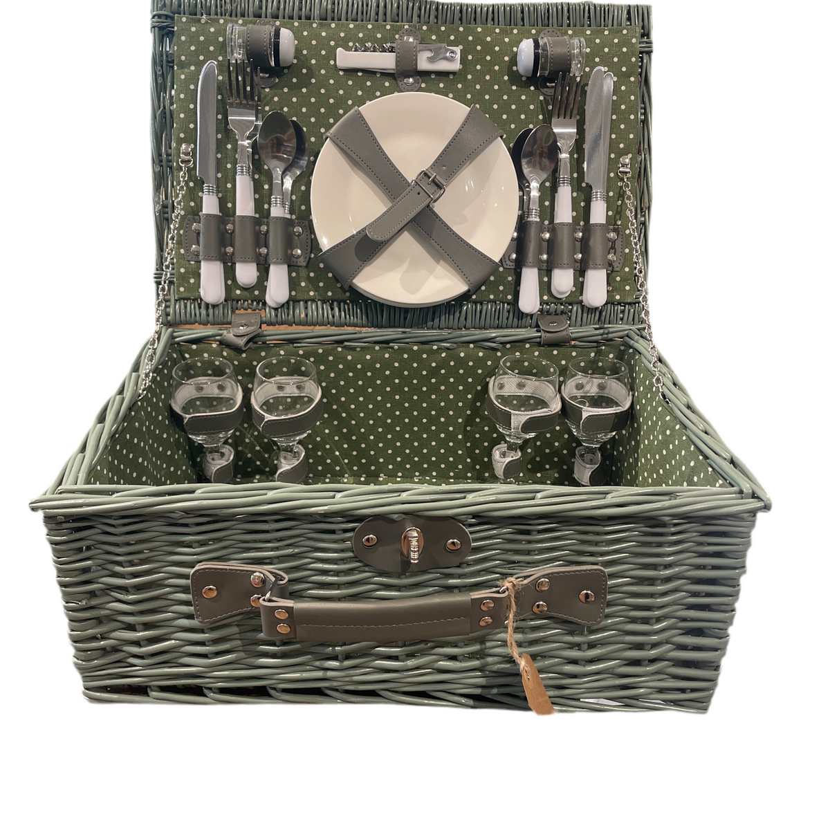 Open woven wicker picnic basket with polka-dot green interior, showing complete service set for four with plates, glasses, cutlery, and accessories