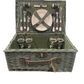 Open woven wicker picnic basket with polka-dot green interior, showing complete service set for four with plates, glasses, cutlery, and accessories