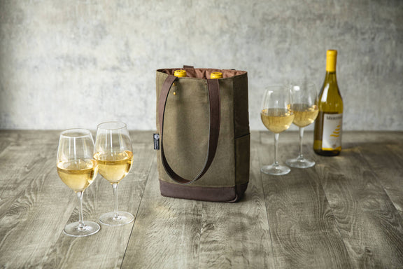 Beige canvas wine tote with brown straps holding two bottles, styled with wine glasses and a bottle on wooden surface