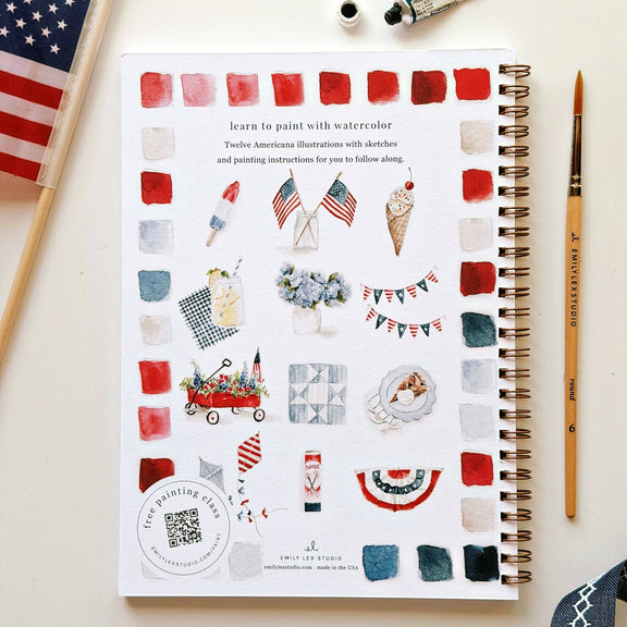 Open watercolor workbook displaying twelve pre-outlined illustrations of American flags, fireworks, ice cream cone, and patriotic bunting alongside watercolor color swatches in reds, blues, and neutrals