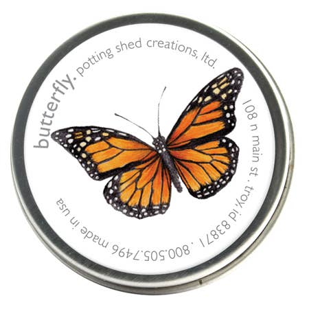 Circular metal seed tin featuring orange and black monarch butterfly illustration on cream background, text printed around edge
