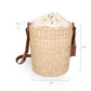 Beige handwoven rush bucket tote with brown leather shoulder straps and drawstring closure