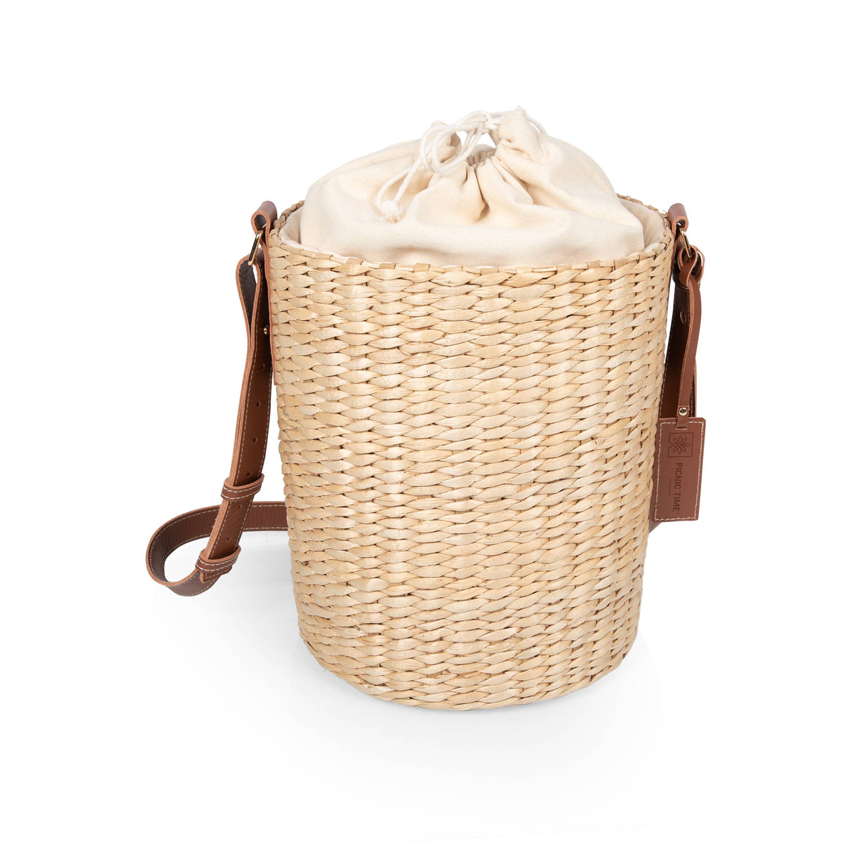 Beige handwoven rush bucket tote with cream canvas drawstring closure and adjustable brown leather shoulder straps