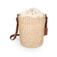 Beige handwoven rush bucket tote with cream canvas drawstring closure and adjustable brown leather shoulder straps