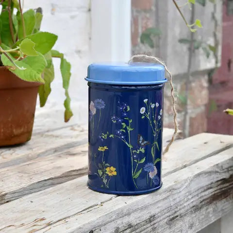 Dark blue tin with floral botanical design holds coiled jute twine with removable lid