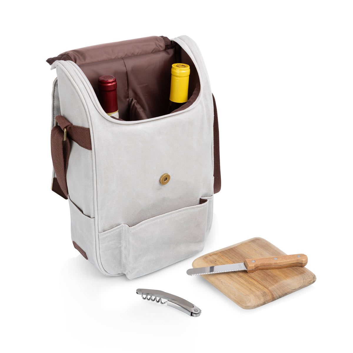 Cream canvas wine tote with brown accents, open to reveal red and yellow wine bottles, wooden cutting board, cheese knives, and metal corkscrew displayed in front.