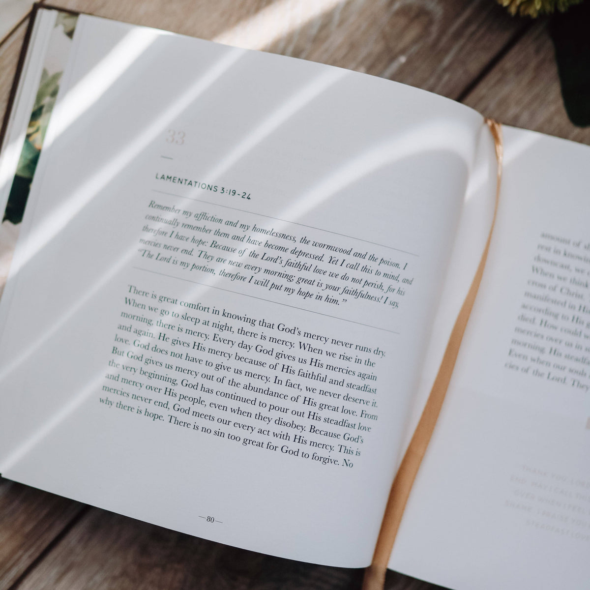 Open devotional book with tan ribbon bookmark, showing Lamentations scripture and devotional text on white pages