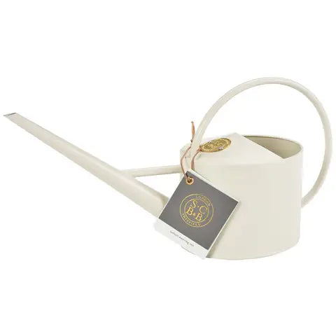 Cream-colored ceramic watering can with curved handle, pointed spout, and attached product tag