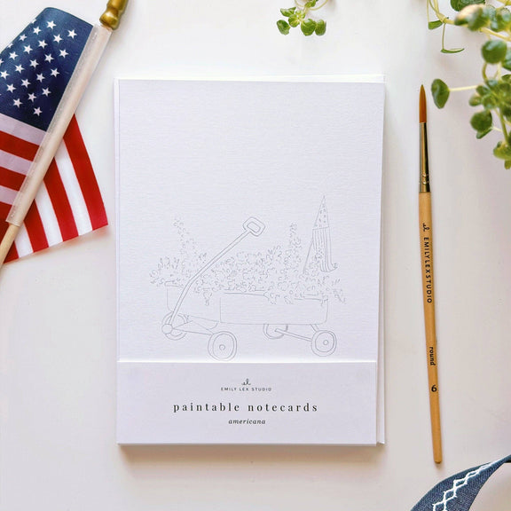 Paintable notecards with American flag and paintbrush on a white surface