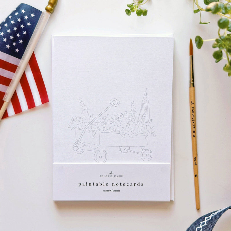 Paintable notecards with American flag and paintbrush on a white surface