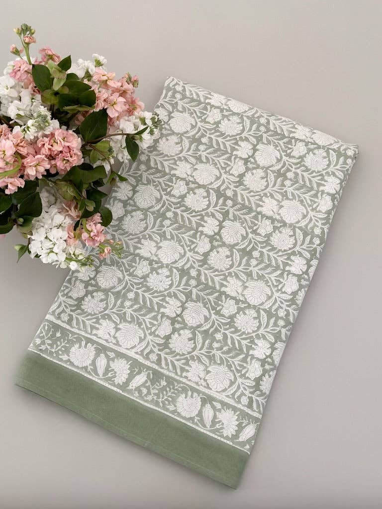 Sage green cotton tablecloth with white botanical floral and leaf print pattern and tonal border detail.