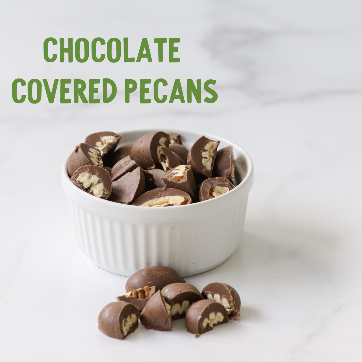 Chocolate-covered pecans displaying golden pecan pieces throughout dark chocolate coating, arranged in a white ceramic bowl on a marble surface