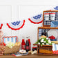 Child holding red "Let Freedom Ring" felt banner surrounded by red, white, and blue patriotic pennant bunting