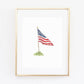Watercolor American flag print in natural wood frame, blue canton with stars, red and white stripes, mounted on pole with green grass base