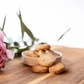 Pecan shortbread cookies in a white ceramic bowl on natural wood surface with fresh pink flowers