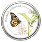 Circular seed packet with monarch butterfly, milkweed plant with pink flowers and green leaves, caterpillars on stems, and metallic silver border