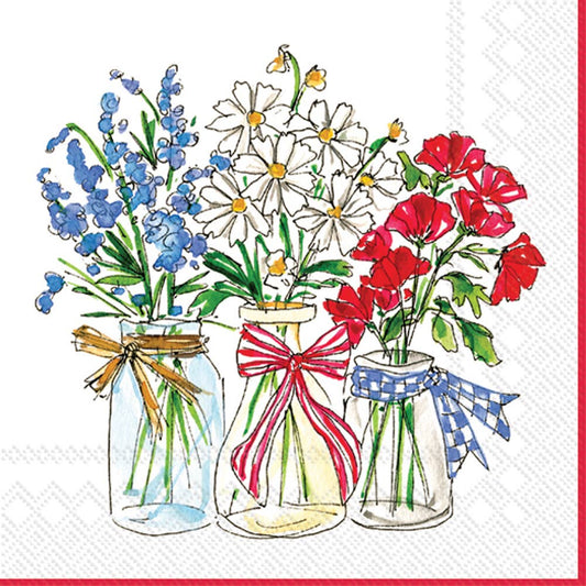 Three glass jars filled with patriotic flowers—blue delphinium, white daisy-like blooms, and red poppies—each tied with coordinating ribbons in gold, red, and blue