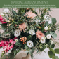 Lush mixed floral arrangement with pink peonies, hot pink spray roses, white roses, coral berries, and cascading green foliage in a dense, romantic display.