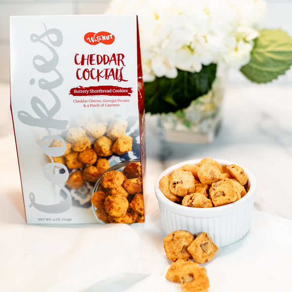 Watanut Cheddar Cocktail buttery shortbread cookies package with golden-brown cheese cookies displayed in white bowl and scattered on surface
