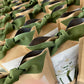 Rows of kraft paper bags tied with sage green ribbon bows, each containing paperwhite bulbs ready to plant