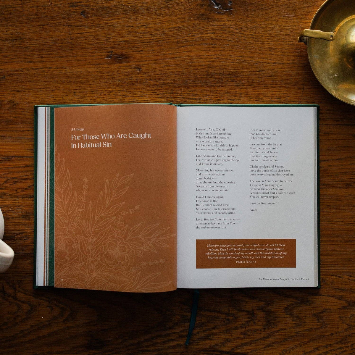 Open book with tan and cream pages on wooden surface showing prayer text and liturgical content
