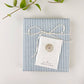 White mini notecard with tan circle monogram on blue-and-white striped fabric, wrapped in white rope bow with greenery