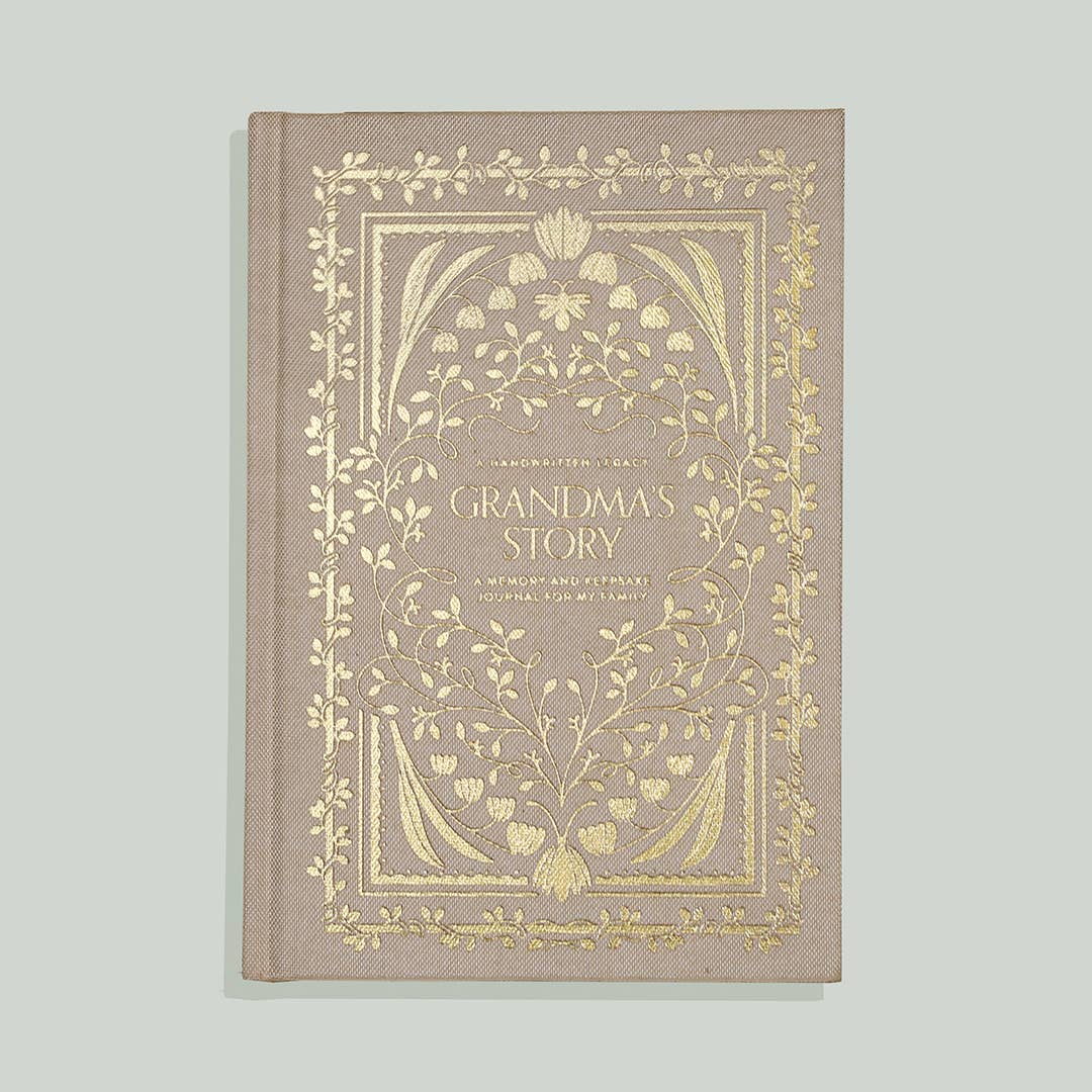 Taupe linen journal with gold foil botanical design, titled "Grandma's Story," featuring ornate floral border and guided pages for family memories