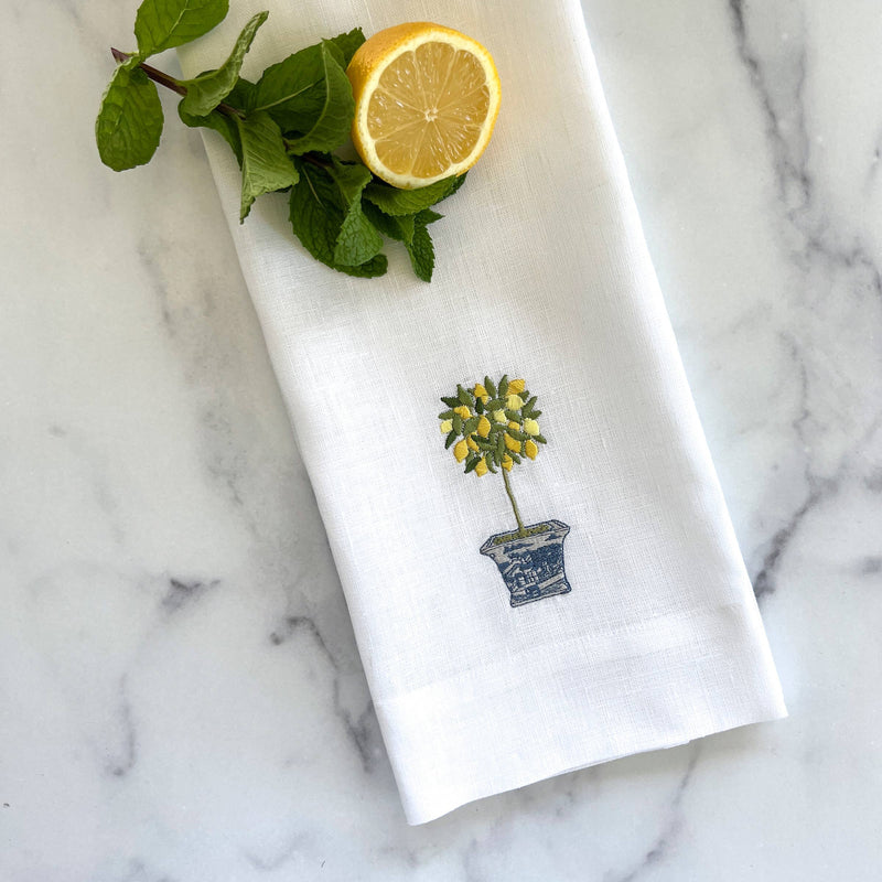 White European linen kitchen towel with yellow potted flower embroidery, displayed on marble with fresh lemon and mint.