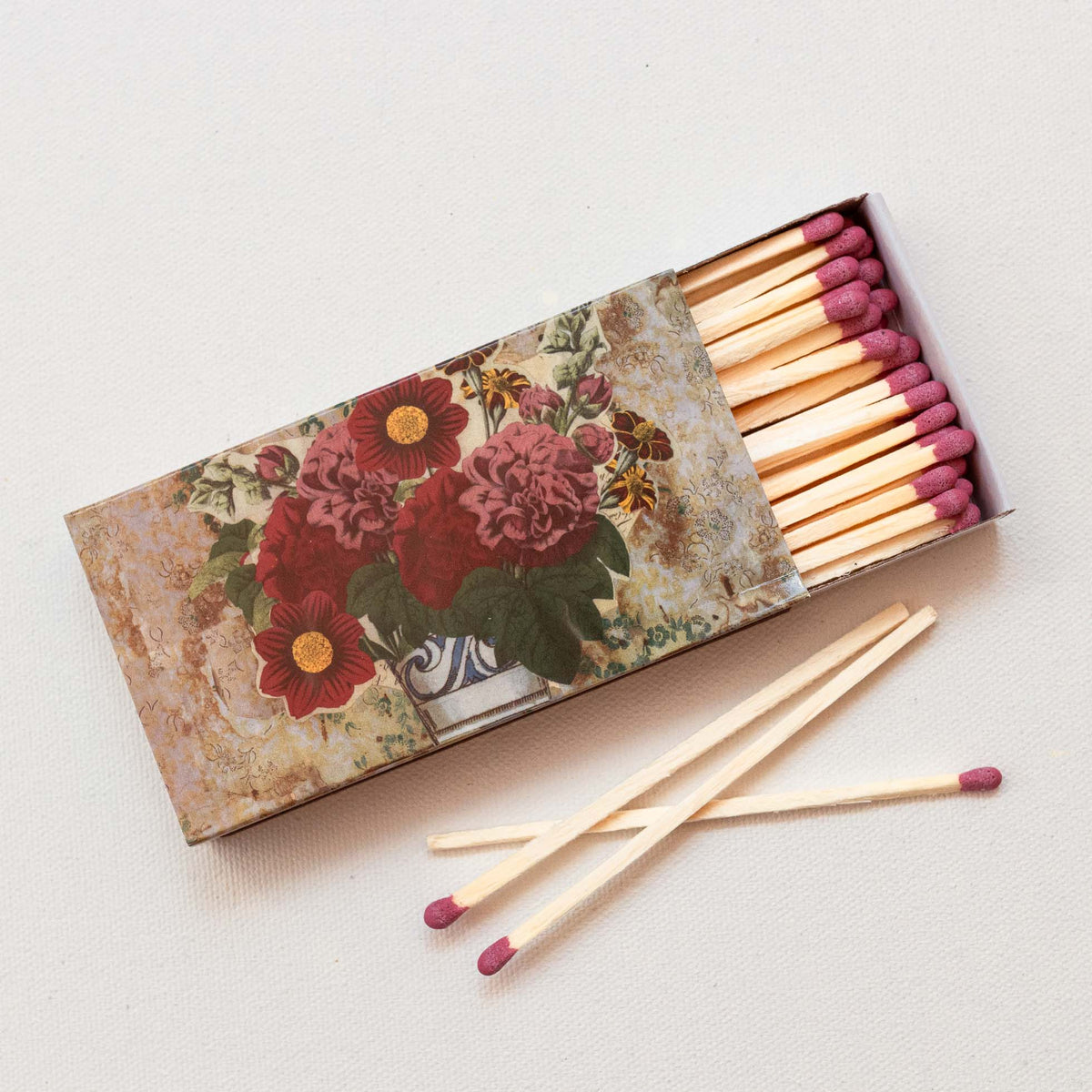 Wooden matches with fuchsia tips in decorative matchbox featuring vintage floral design with red and yellow flowers