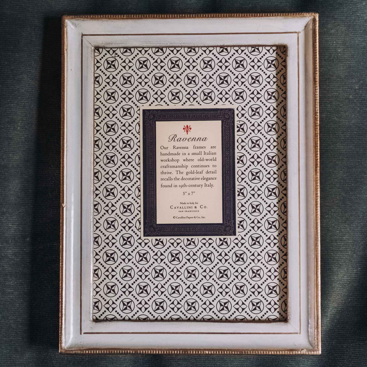 Cream-colored wooden frame with gold leaf border and geometric patterned mat featuring a small informational card