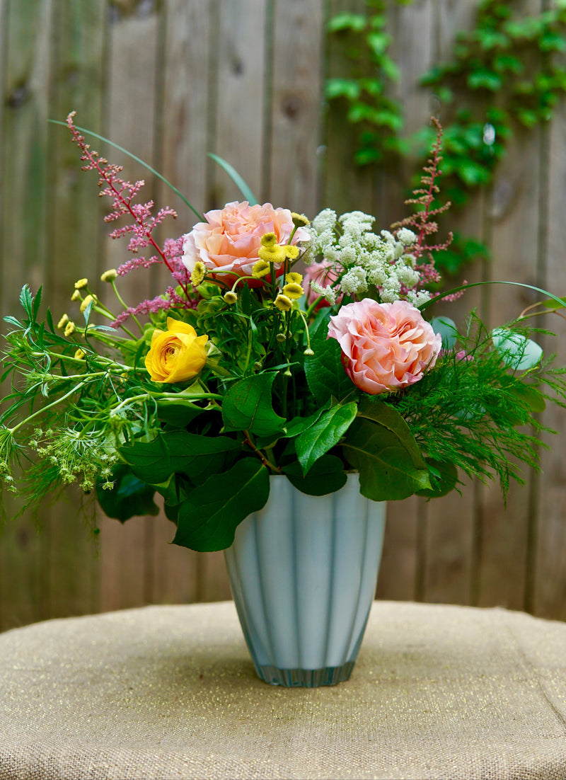 Floral arrangement in a vase on a table with a wooden background