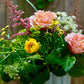 Bouquet of flowers with greenery in a vase against a wooden background
