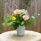 Floral arrangement in a white vase on a table with a wooden background