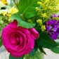 Bouquet of flowers including a pink rose, yellow sunflower, and green leaves.