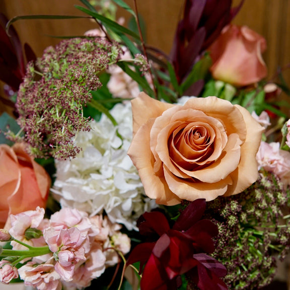 Colorful flower arrangement with roses and hydrangeas on a wooden surface