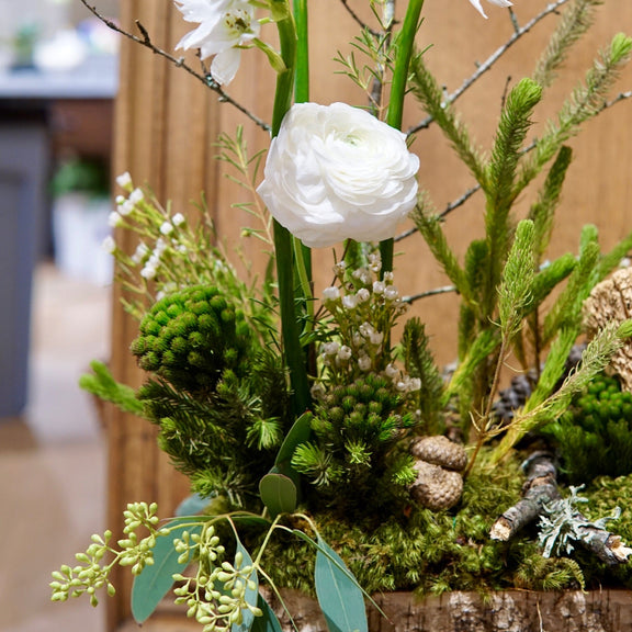 Floral arrangement with white flowers and greenery in a wooden planter.