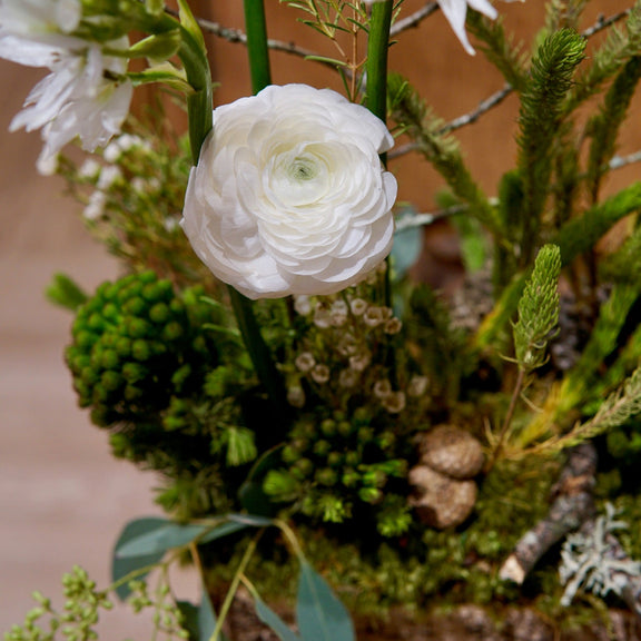 Floral arrangement with white flowers and greenery on a wooden surface