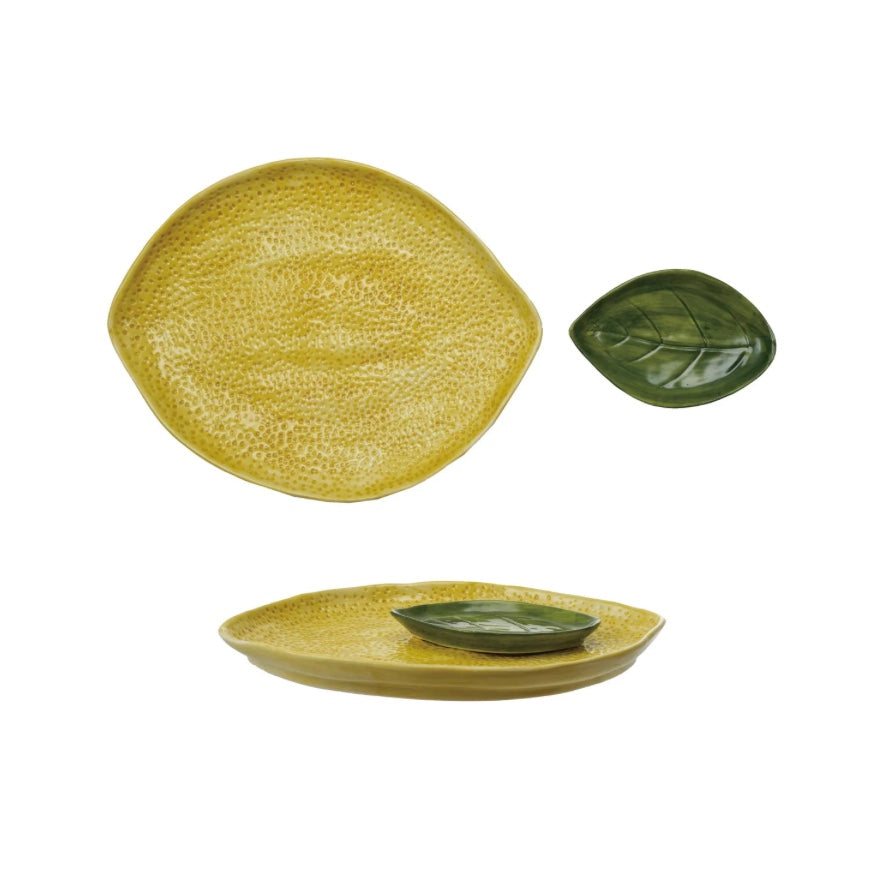 Yellow stoneware lemon-shaped platter with dimpled texture and matching green leaf-shaped dish set