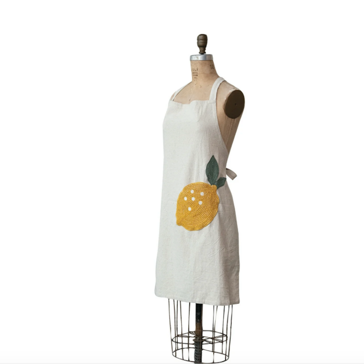 Cream cotton and linen apron with textured yellow lemon and green leaf embellishment on front pocket